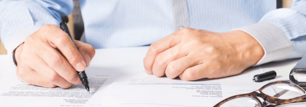 Hands writing on documents with glasses
